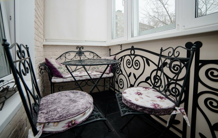 Cadeiras forjadas na varanda com janelas de plástico