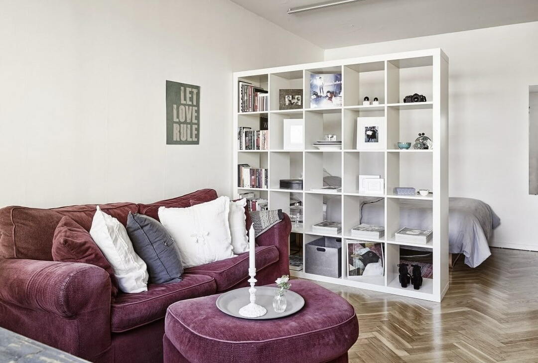 Unidad de estantería blanca como partición en un apartamento tipo estudio