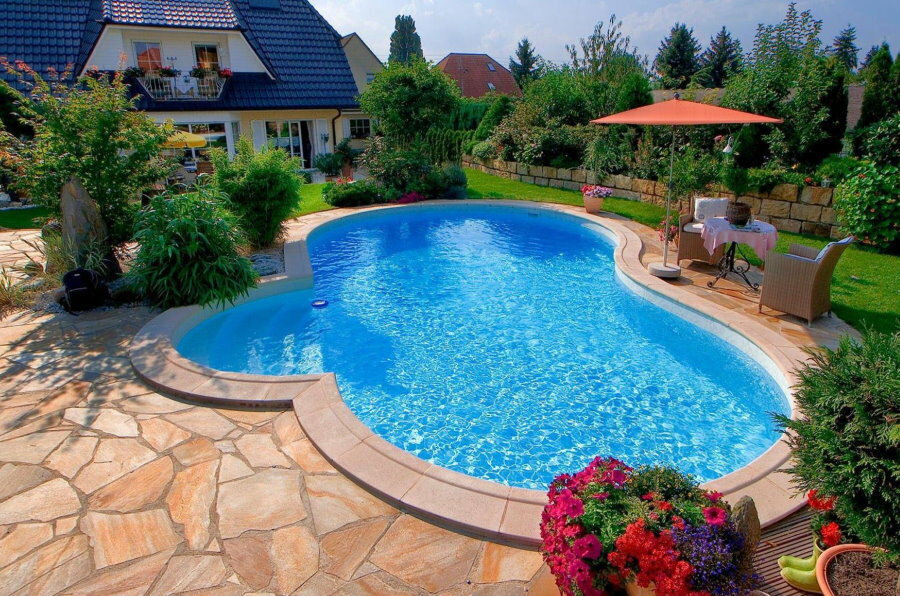 Terraza de piedra frente a la piscina de agua azul.
